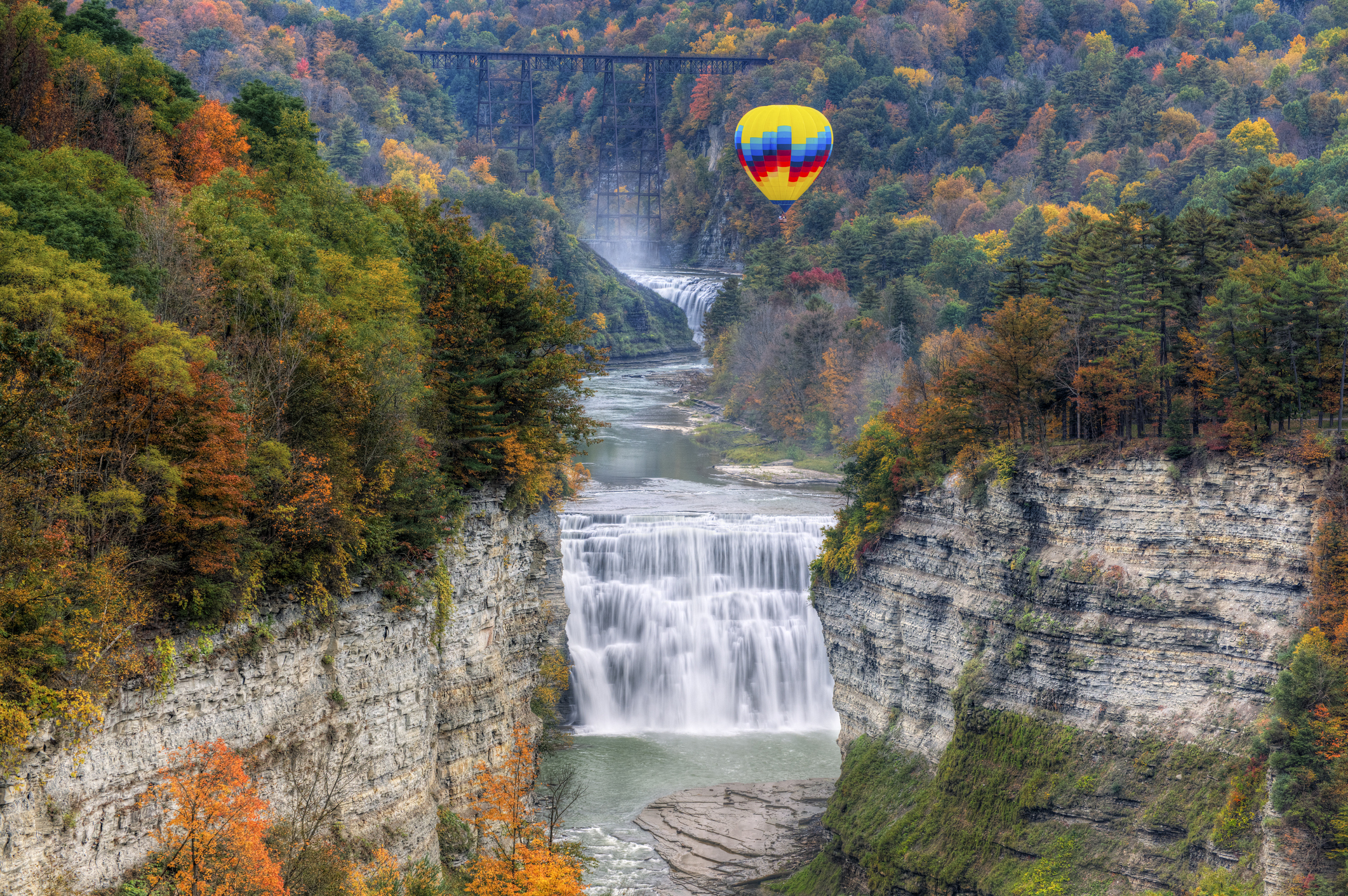 A hot air balloon flies over waterfalls in Letchworth State Park in New York State